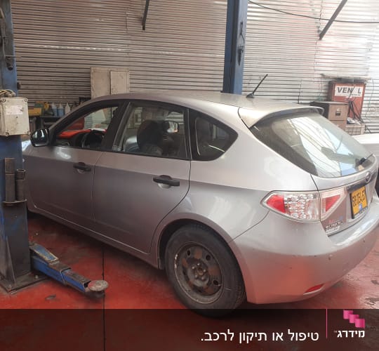 מכונית אפורה במוסך על רצפת בטון אדומה